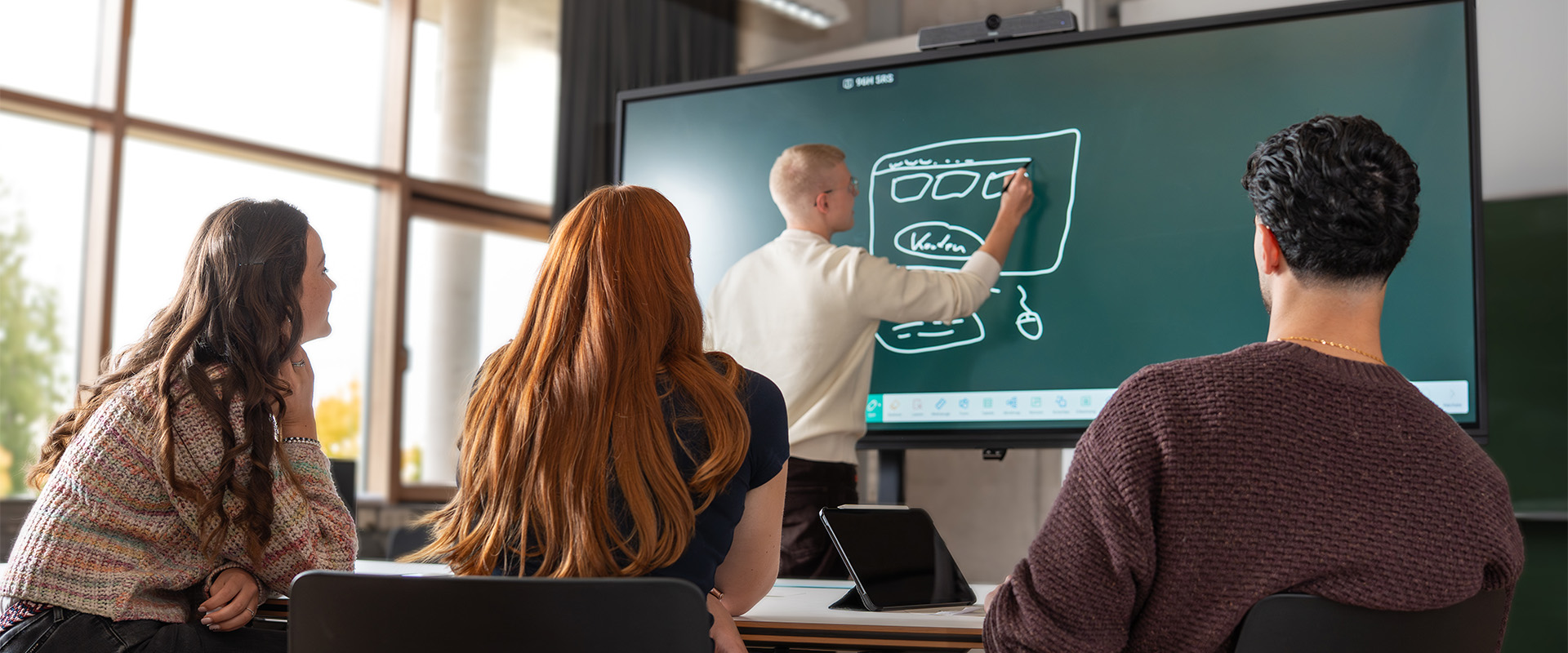 Studierendengruppe sitzt im Projektraum und arbeitet gemeinsam am Touch-TV