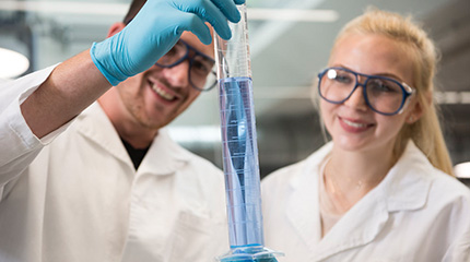 Zwei Studierende des Studiengangs Werkstoff- und Prozesstechnik begutachten ein Reagenzglas beim Laborpraktikum Chemie